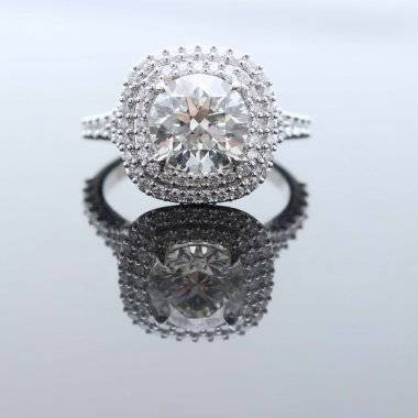 Halo engagement ring reflected on a glossy surface